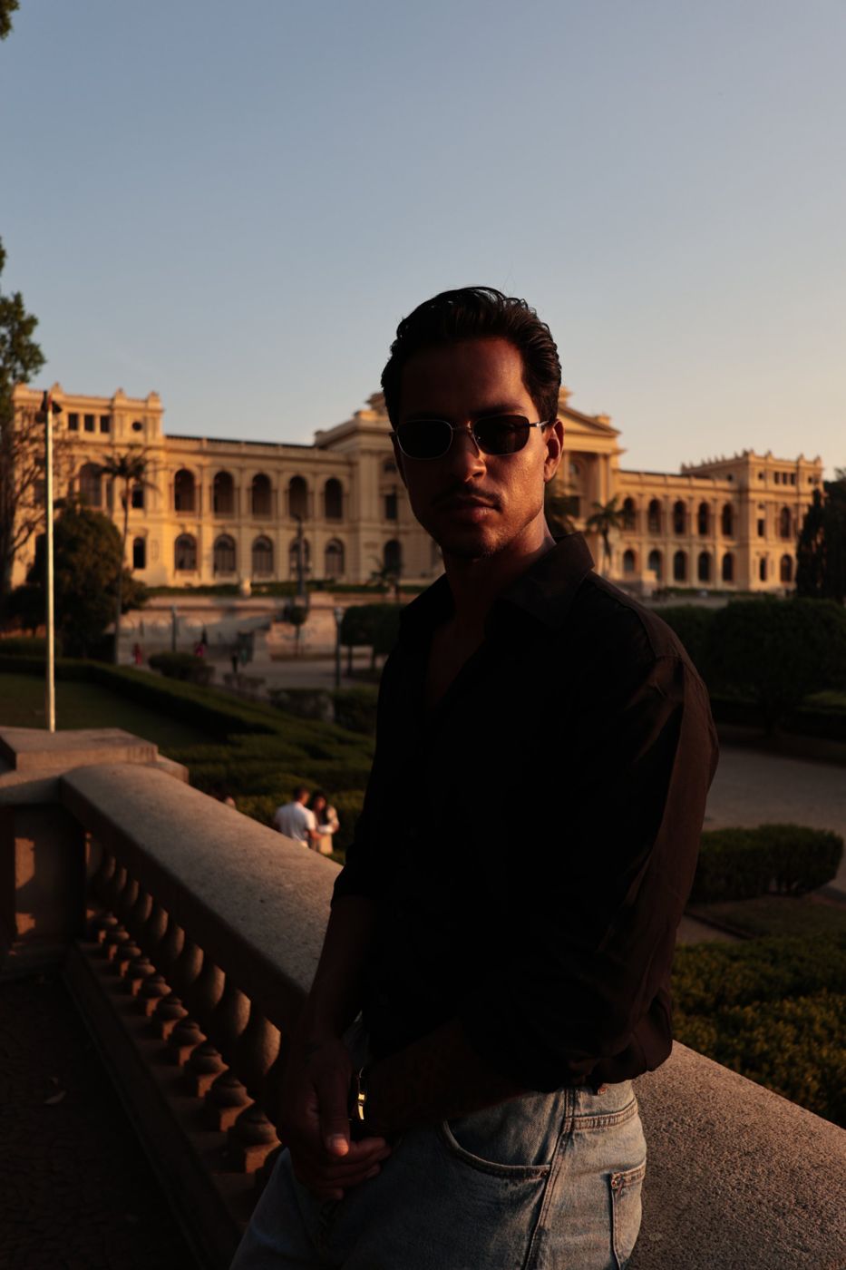 Lucas de óculos escuros ao pôr do sol diante do Museu do Ipiranga